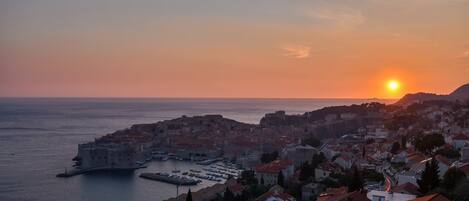 A coastal cityscape with a prominent historic building by the sea, a marina, and residential areas.