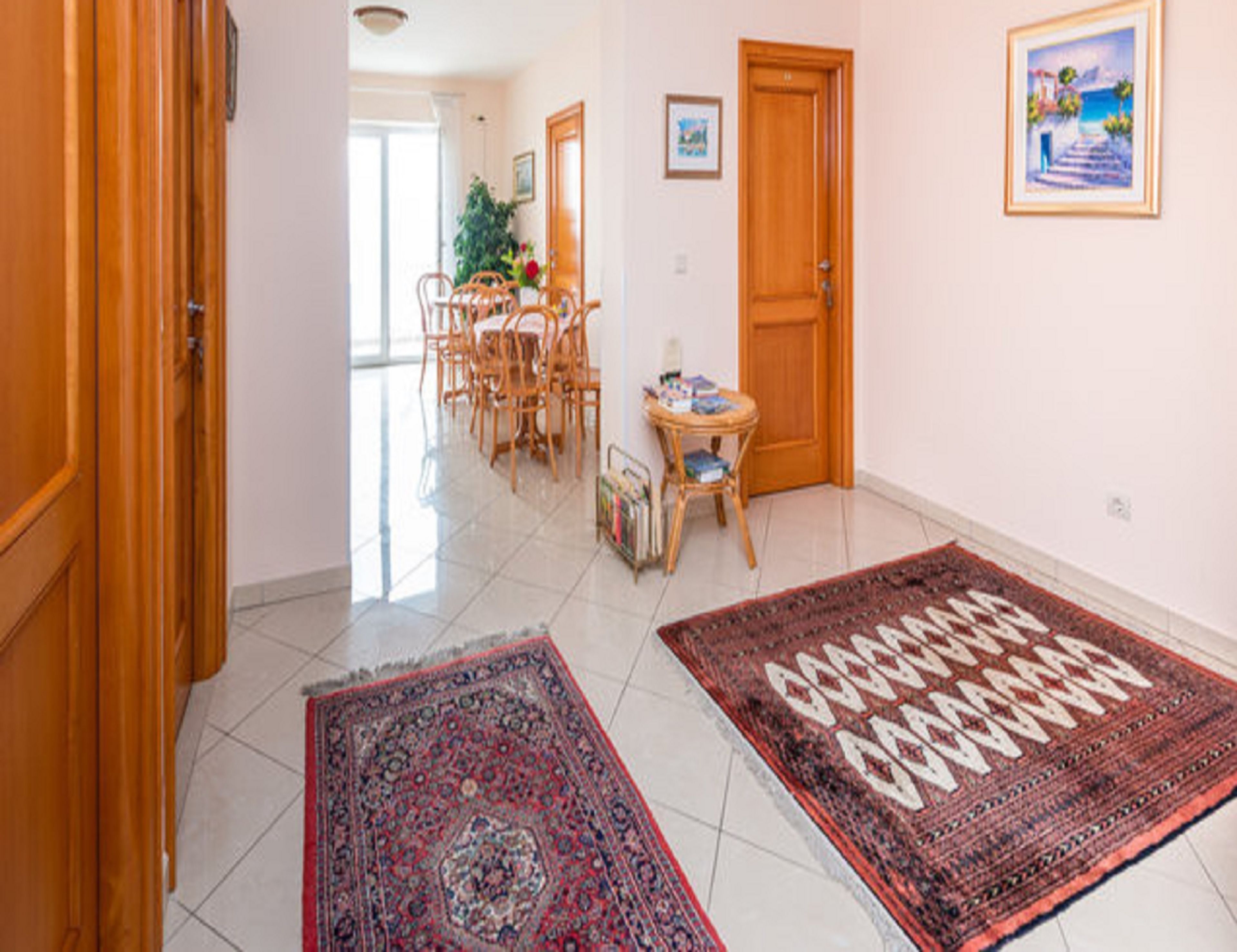 Un couloir comprenant un coin repas, des portes en bois et un tapis orné d’un motif géométrique.