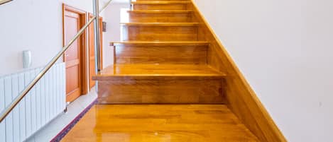 A wooden staircase with a handrail and a carpeted landing.