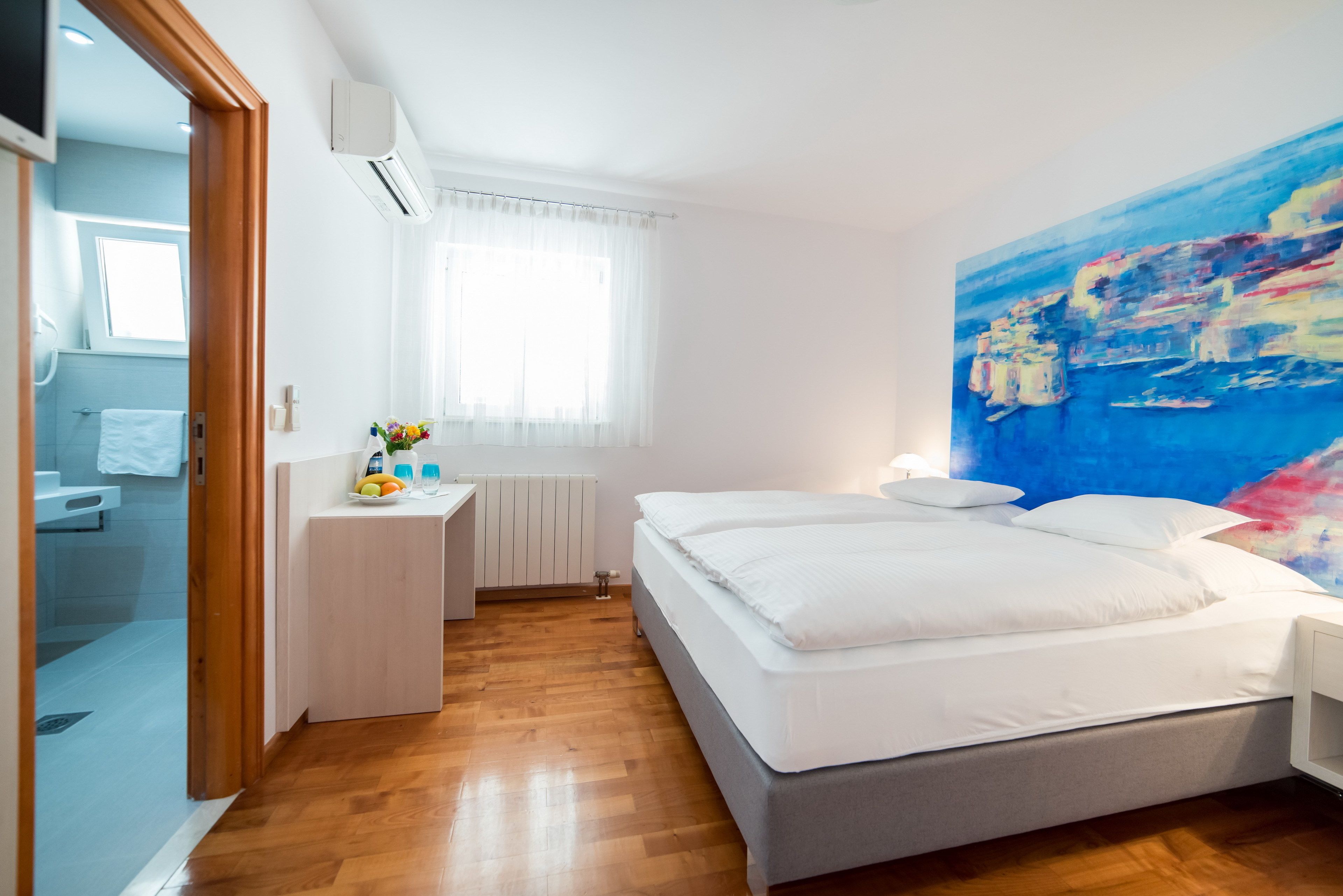 A bedroom with a bed, bedside table, and a painting on the wall.