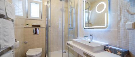 Un baño moderno con cabina de ducha de vidrio, un lavabo blanco y un inodoro.