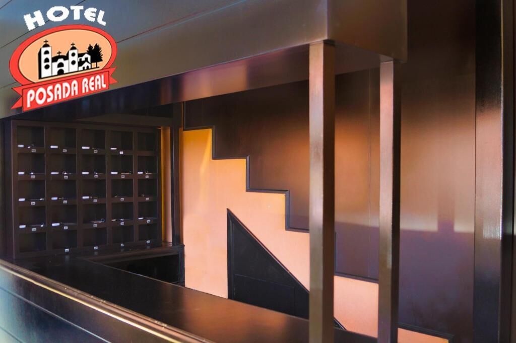 A hotel reception area with a modern design, featuring a reception desk and a staircase.