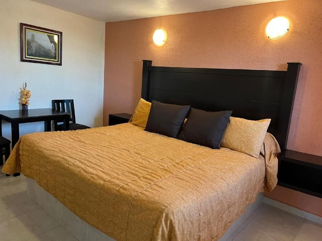 Una cama con cabecera, dos mesitas de noche y una silla.