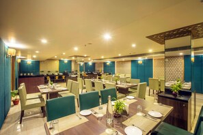 Un restaurante con varias mesas y sillas, una zona de bufé y una cocina al fondo.