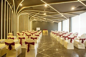 Un salón de conferencias con hileras de sillas, un escenario y un diseño moderno en el techo.