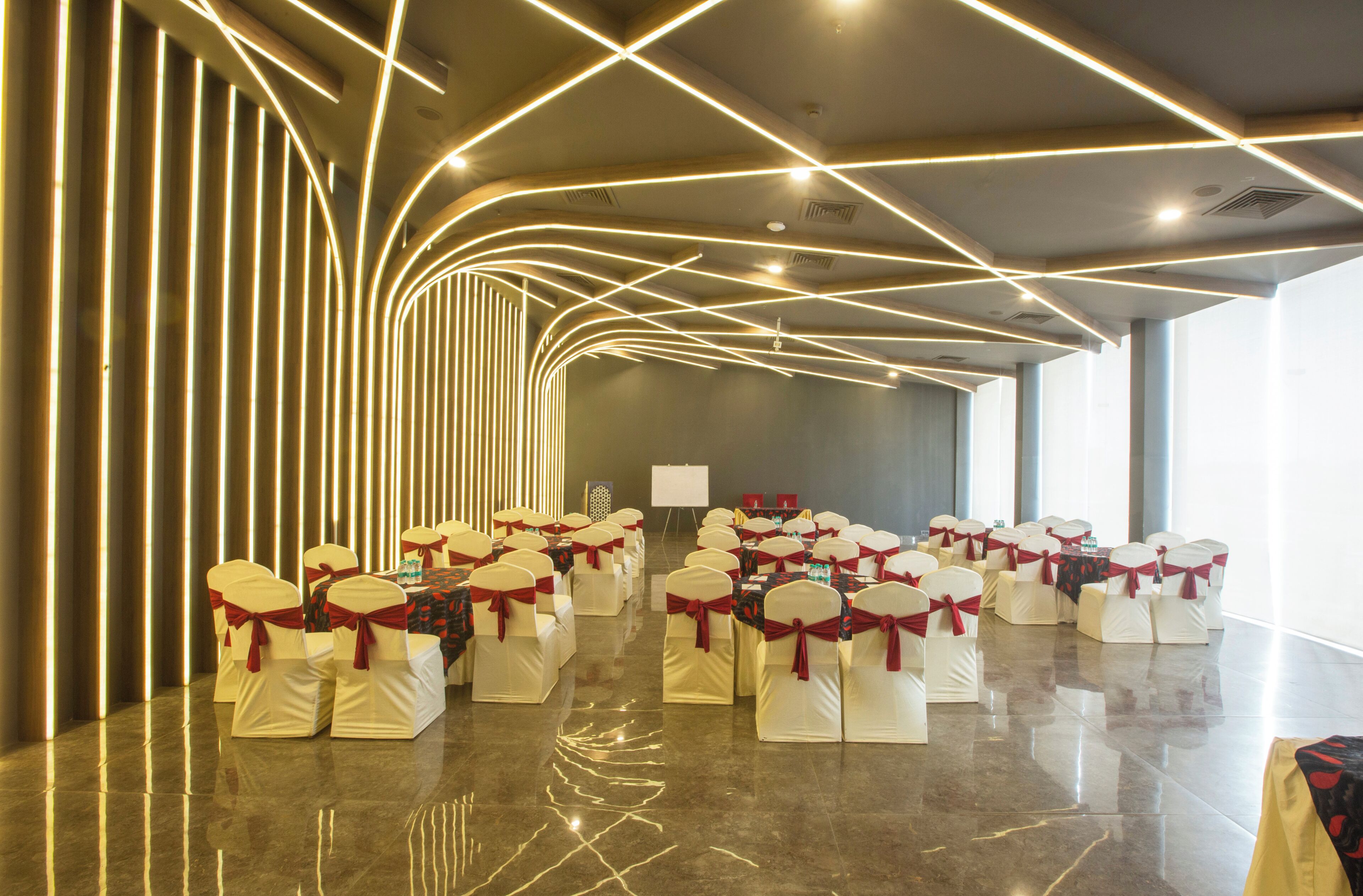 A conference room with rows of chairs, a whiteboard, and a modern ceiling design.