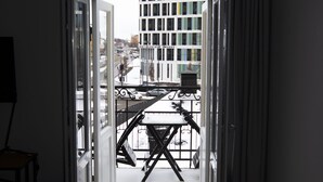 An open door leading to a balcony with a view of buildings and a snowy street. - Livin Station (Örebro)