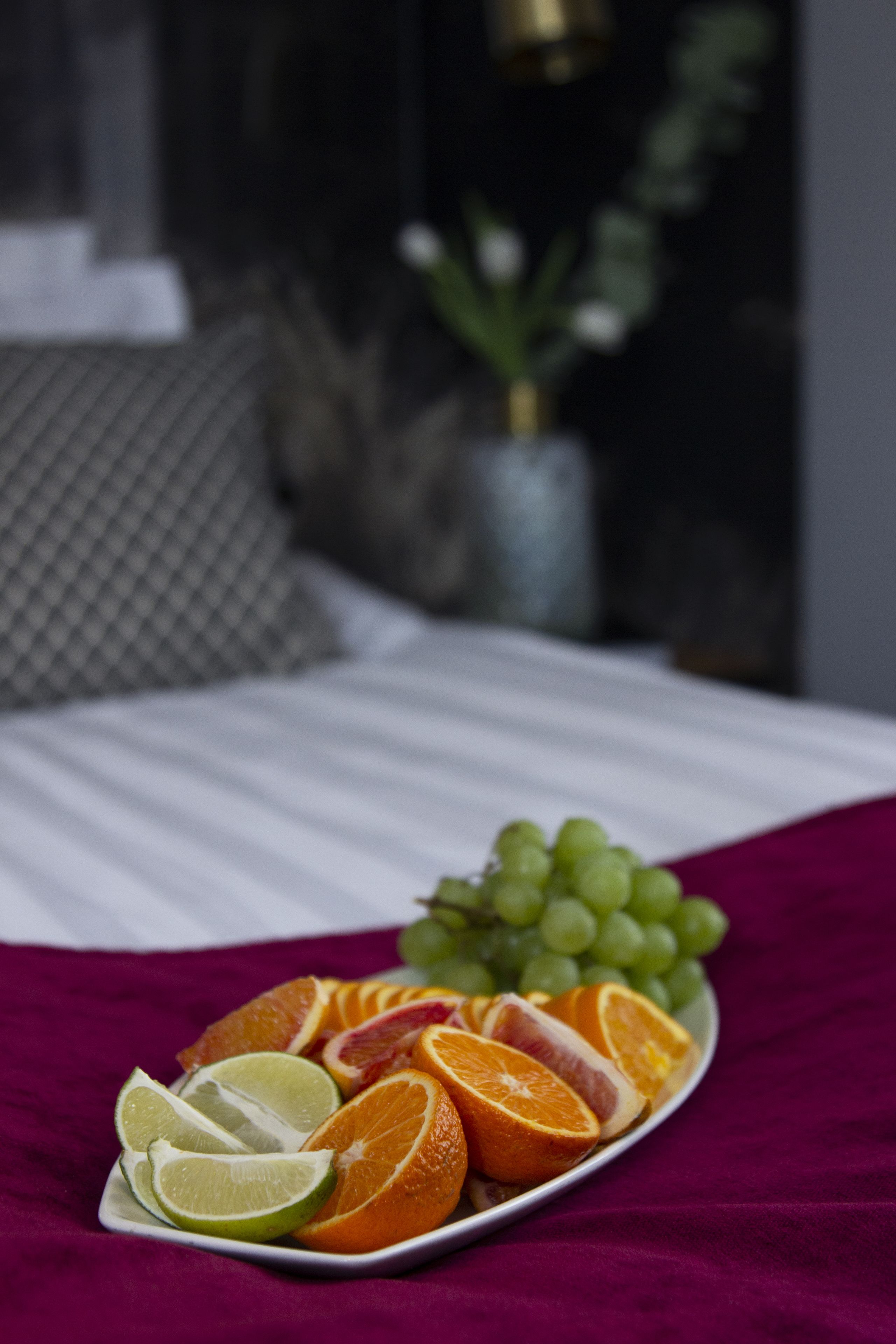 A bed with a white bedspread and a plate of fruit on it.