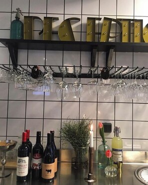 A bar area with wine bottles, glasses, and a decorative sign. - Livin Station (Örebro)