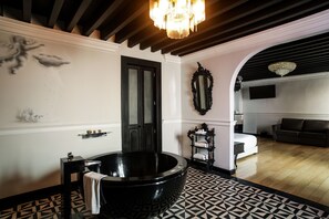 Un baño moderno con una bañera independiente, tocador y un espejo grande.