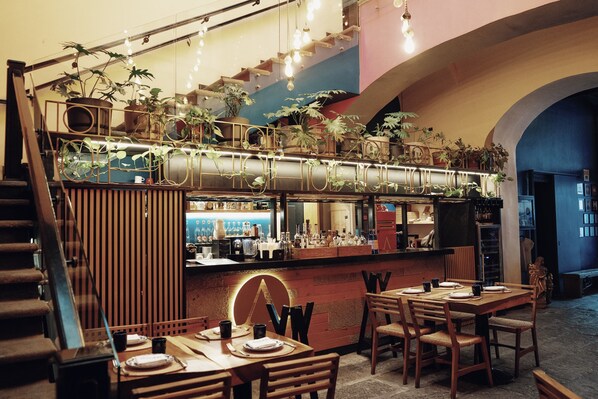Un restaurante con área de bar, sillas y mesas de madera.