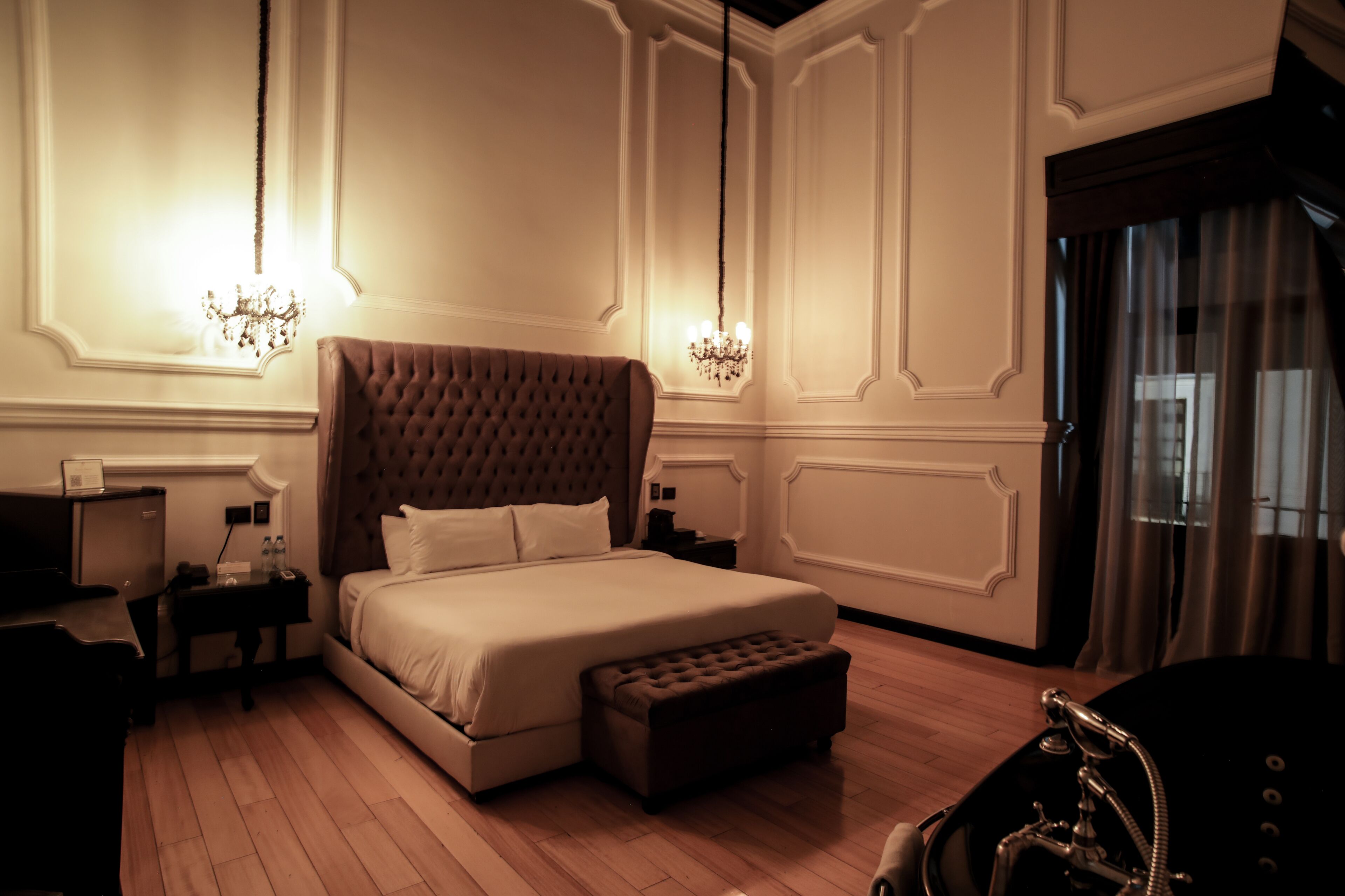 A bedroom with a large bed, a nightstand, a dresser, and a chandelier.