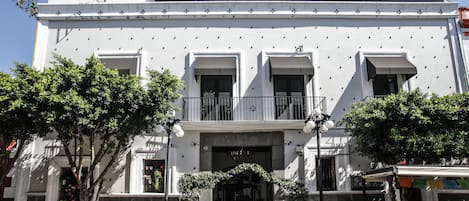 Un bâtiment blanc doté d’un balcon, d’une porte et d’une fenêtre.