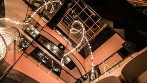 Un atrio de varios niveles con arquitectura moderna, que presenta barandillas de vidrio e iluminación decorativa.