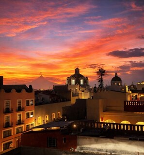 Un paisaje urbano al atardecer con edificios y una cúpula destacada.