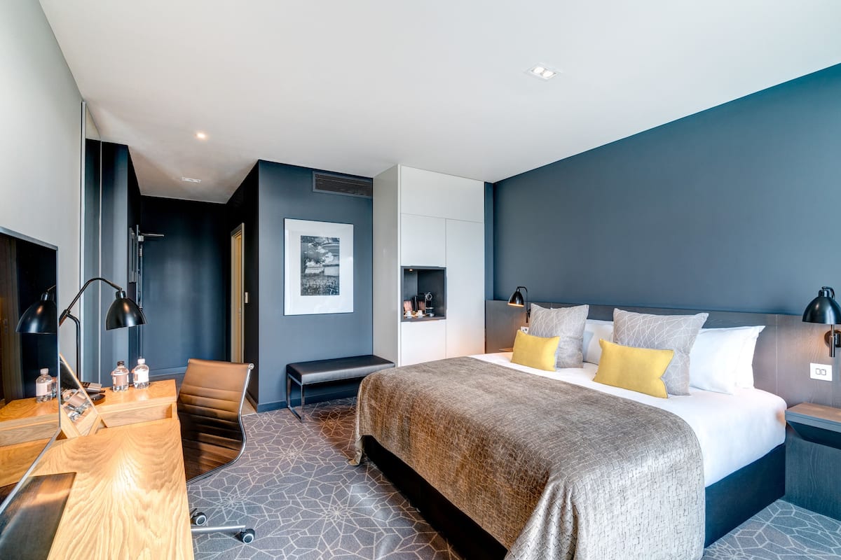 Ein modernes Hotelzimmer mit einem großen Bett, einem Schreibtisch, einem Sessel und einer Bank.