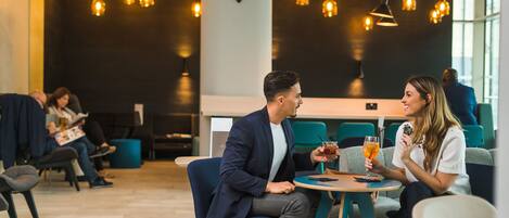 A modern indoor setting with seating areas, tables, and hanging pendant lights.