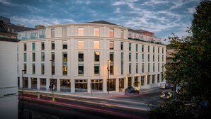 A modern hotel with a curved facade, large windows, and a ground-level entrance. - Apex City of Bath Hotel (Bath)
