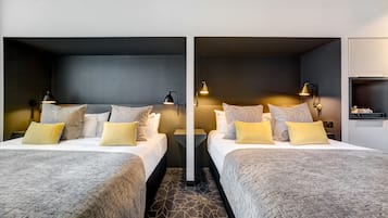 Una camera d'albergo con due letti, ognuno dotato di comodino, lampade e cuscini decorativi.