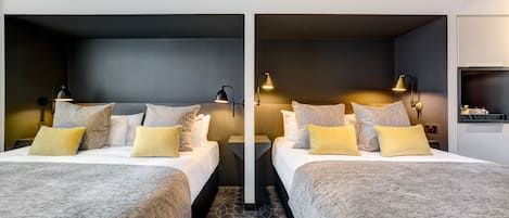 A hotel room with two beds, each with a nightstand, lamps, and decorative pillows.