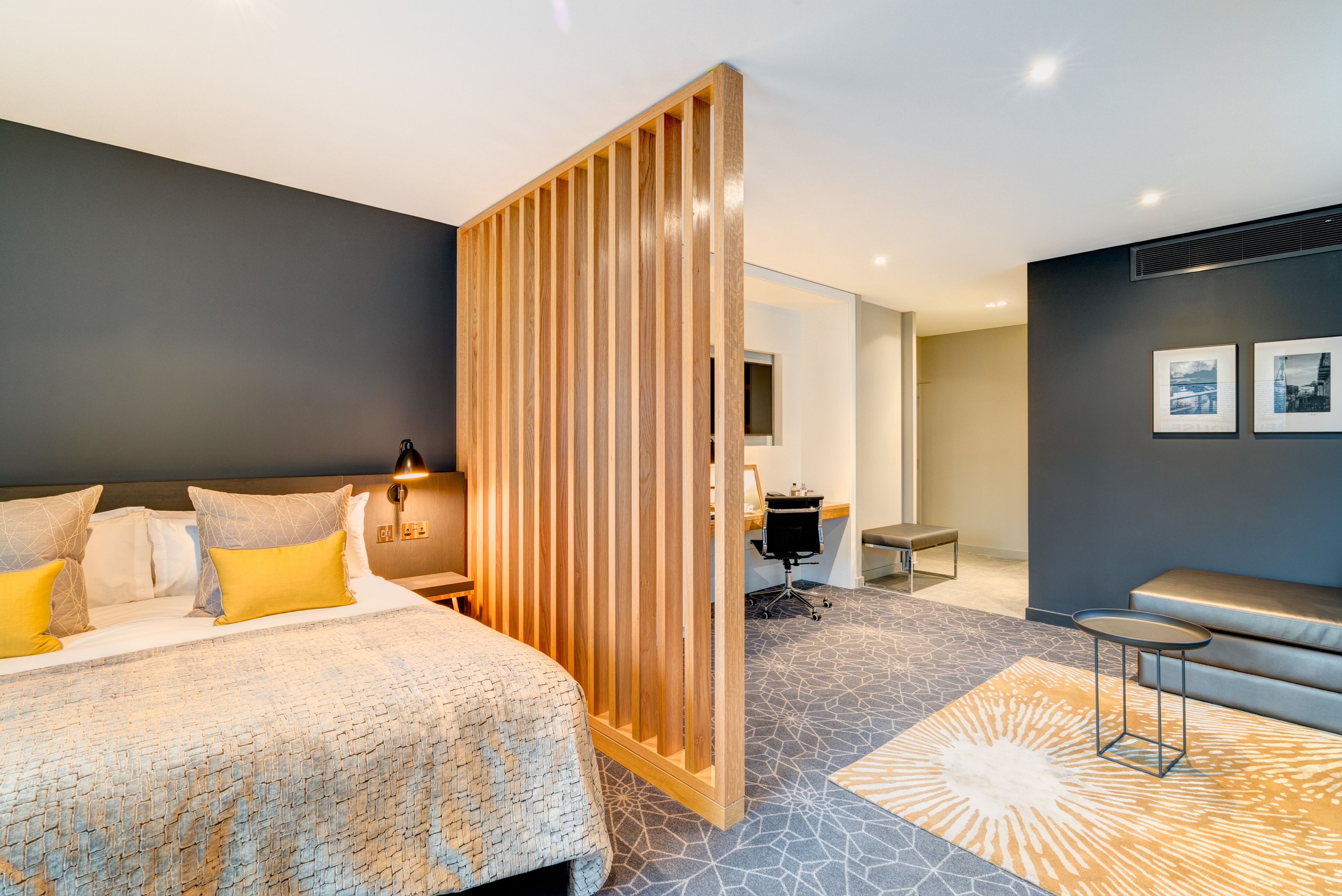 A modern hotel room with a large bed, a desk, and a seating area.