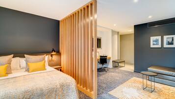 A modern hotel room with a large bed, a desk, and a seating area.