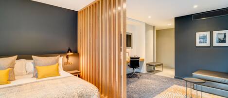 Una habitación de hotel moderna con una cama grande, un escritorio y un área de descanso.