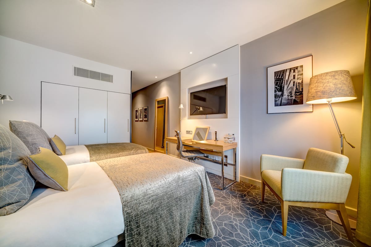 Ein Hotelzimmer mit einem Bett, einem Schreibtisch, einem Stuhl und einer Lampe.