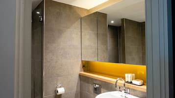 A modern bathroom with a large mirror, a sink, and a toilet.