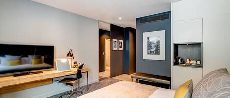 Habitación de hotel moderna con una cama grande, un escritorio con computadora, un televisor de pantalla plana y un pequeño rincón de descanso.