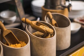 A kitchen area with several beige containers holding food items, each with a wooden scoop.
