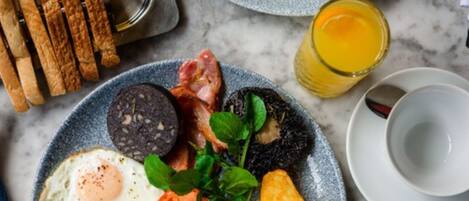 Un plato de desayuno con huevos, tocino, morcilla y tostadas.