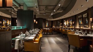 A restaurant with long tables, chairs, and a modern interior design. - Dakota Leeds (Leeds)