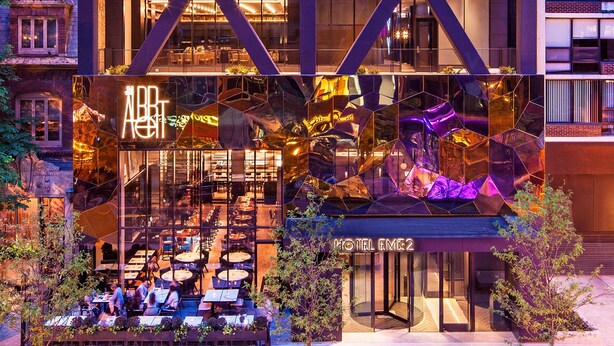 A modern hotel with a glass facade, outdoor seating, and a prominent 'ABT' sign. - Hotel EMC2, Autograph Collection (Chicago)