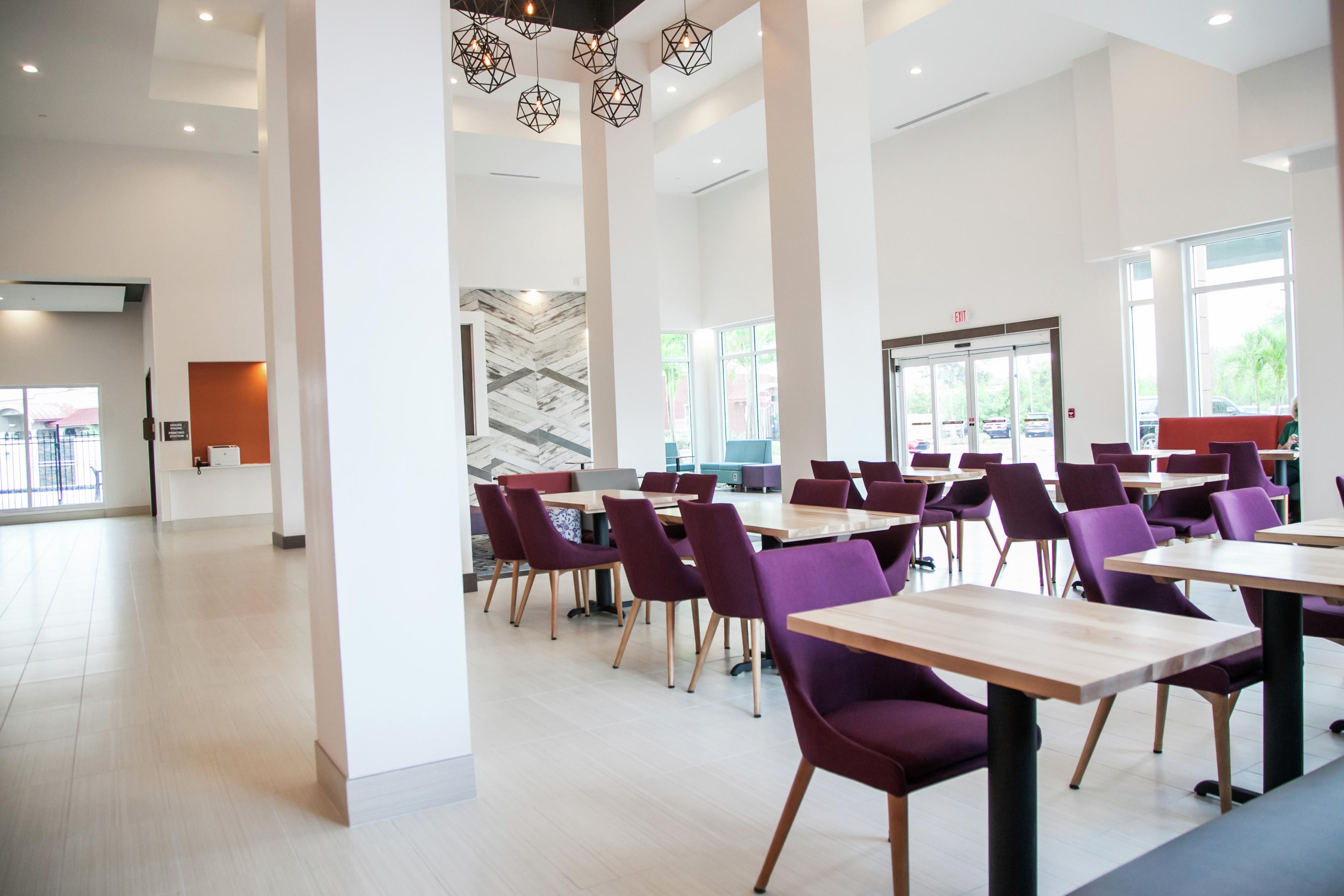 Un comedor amplio con techos altos, iluminación colgante moderna y vistas al exterior gracias a grandes ventanales.