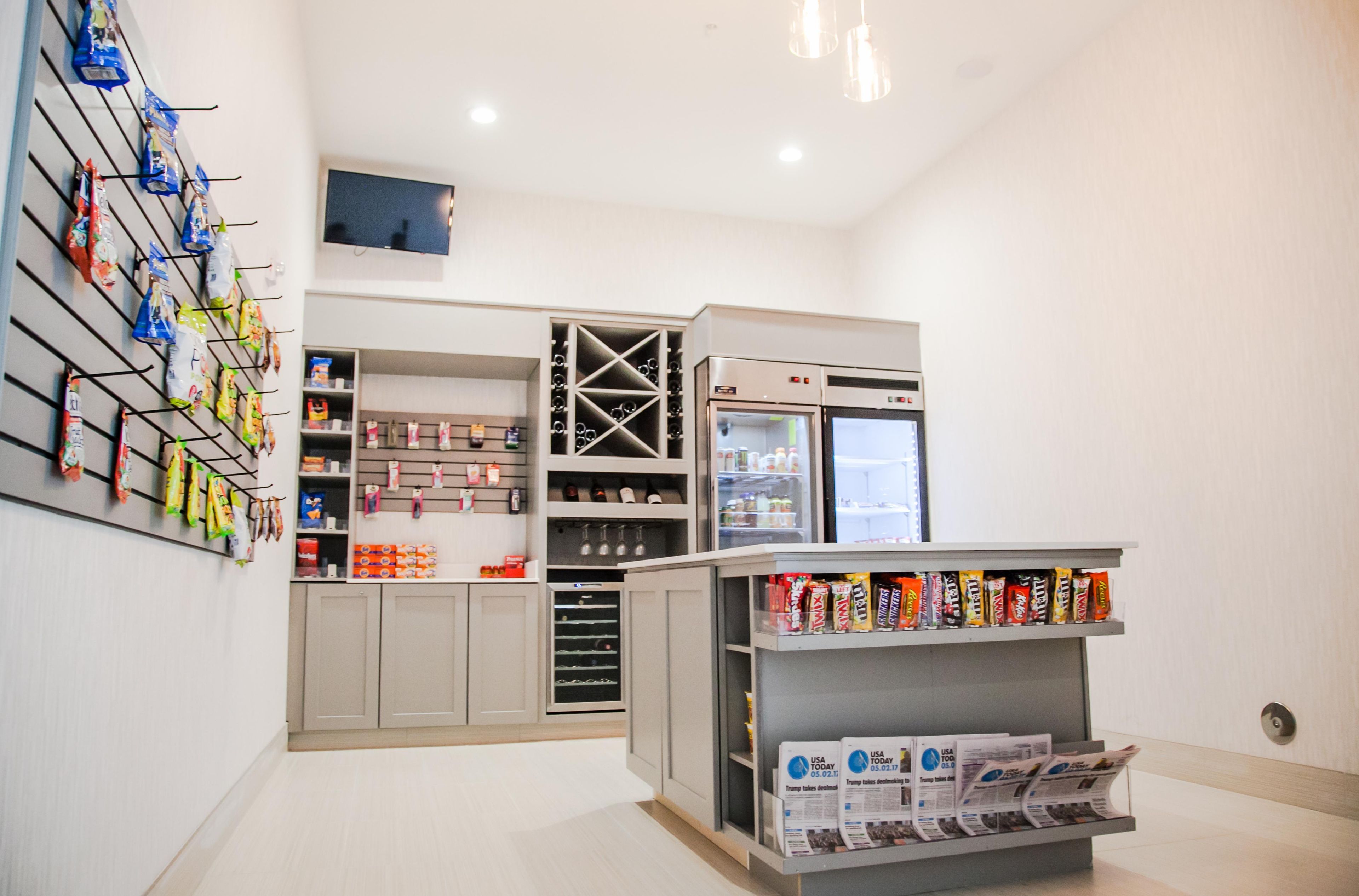 A modern kitchen with built-in appliances, a wine cooler, and a variety of snacks and beverages on shelves.