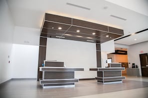 A reception area with two reception desks, a modern ceiling design, and a visible exit sign.