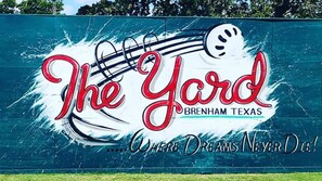 A sign for "The Yard" in Brenham, Texas, featuring a musical note and a baseball cap. - Holiday Inn Express & Suites Brenham South by IHG (Brenham)