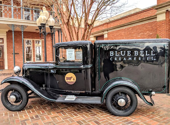 A vintage black truck parked in front of a brick building with a sign reading "BLUE BELL CREAMERIES." - Holiday Inn Express & Suites Brenham South by IHG (Brenham)