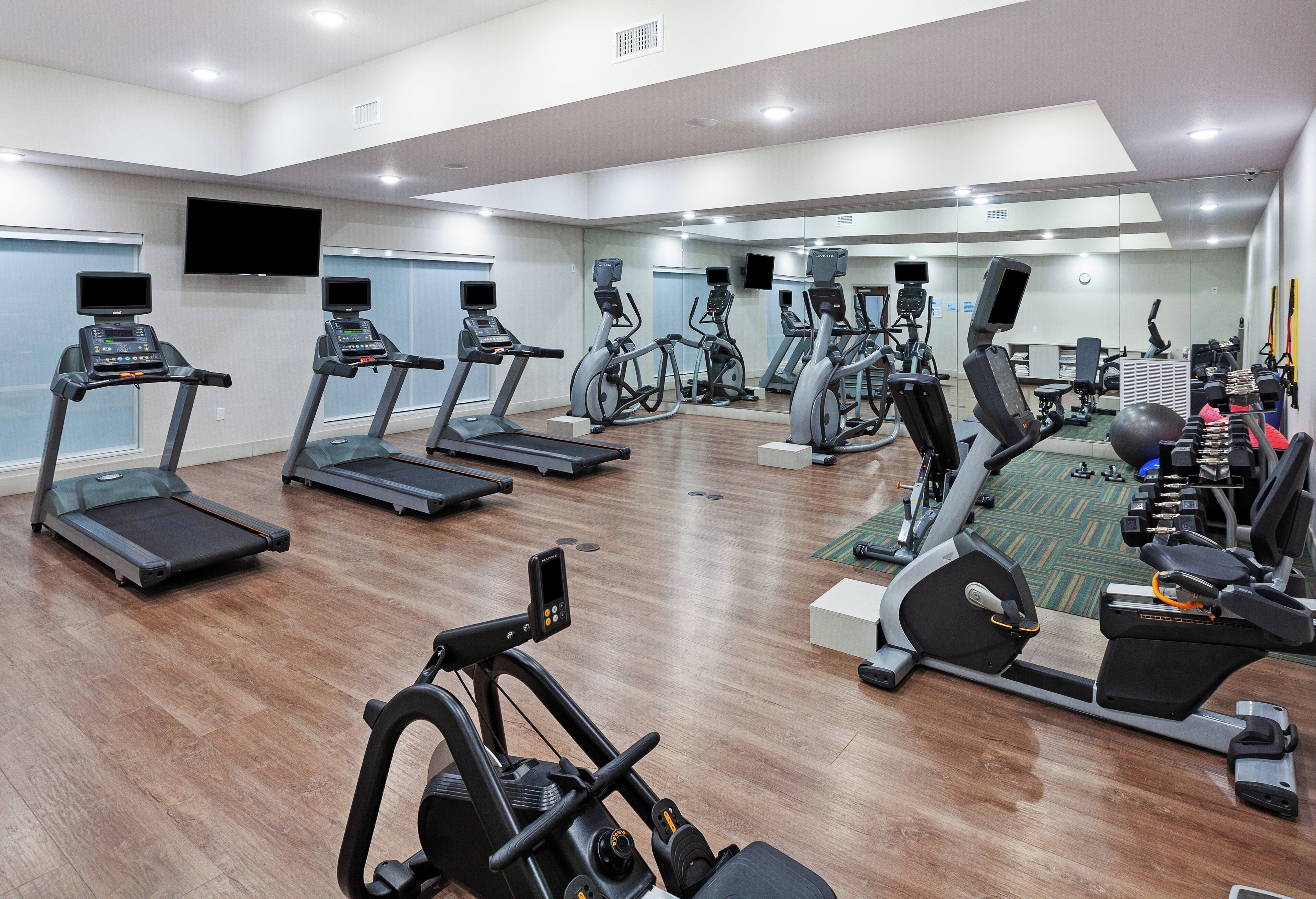 A gym with multiple treadmills, stationary bikes, and elliptical machines.
