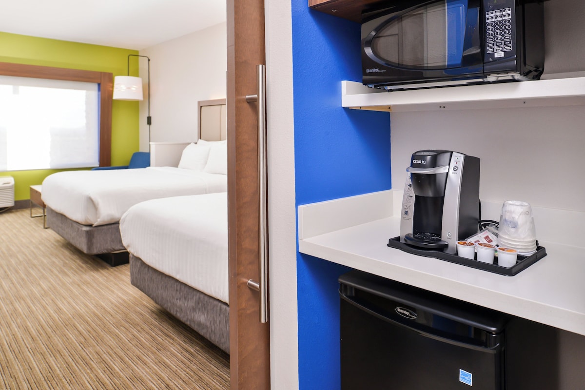 A hotel room with two beds, a microwave, a coffee maker, and a dishwasher.