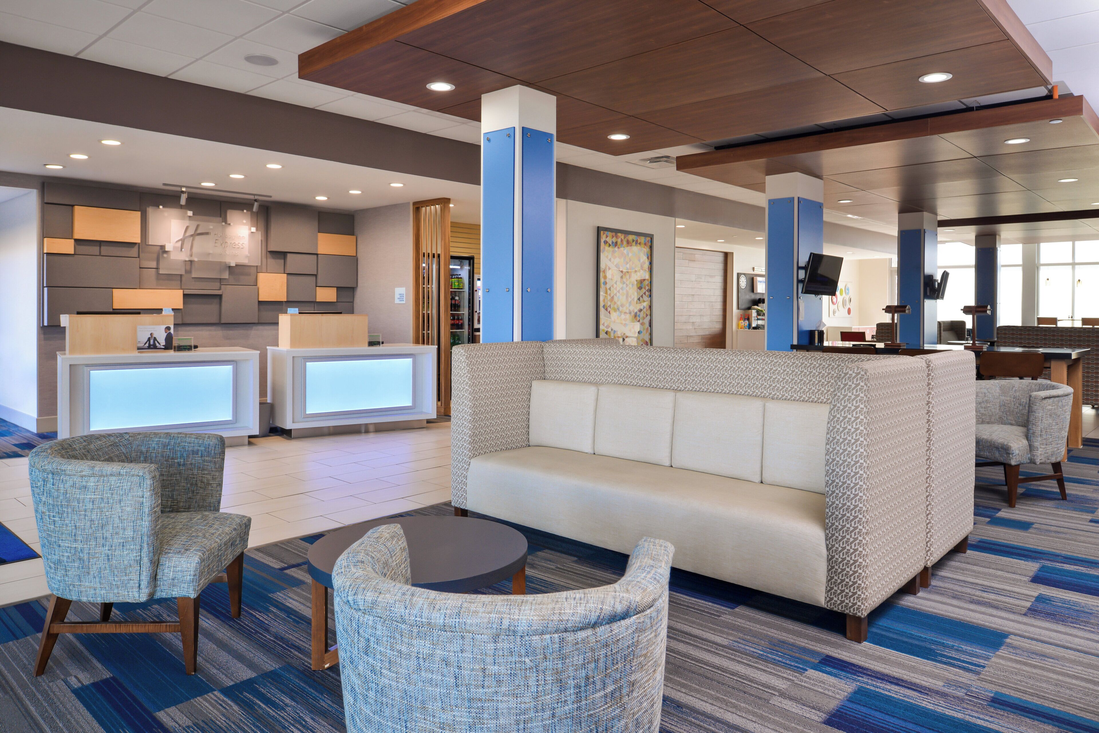 A hotel lobby with a reception desk, seating area, and a television mounted on the wall.