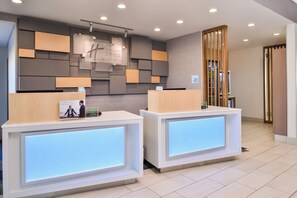 A hotel reception area with two reception desks, a wall-mounted sign, and a check-in counter.