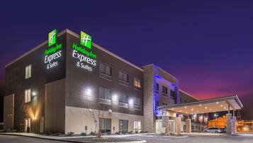 A Holiday Inn Express & Suites hotel with a modern design, featuring a prominent sign and a well-lit entrance.