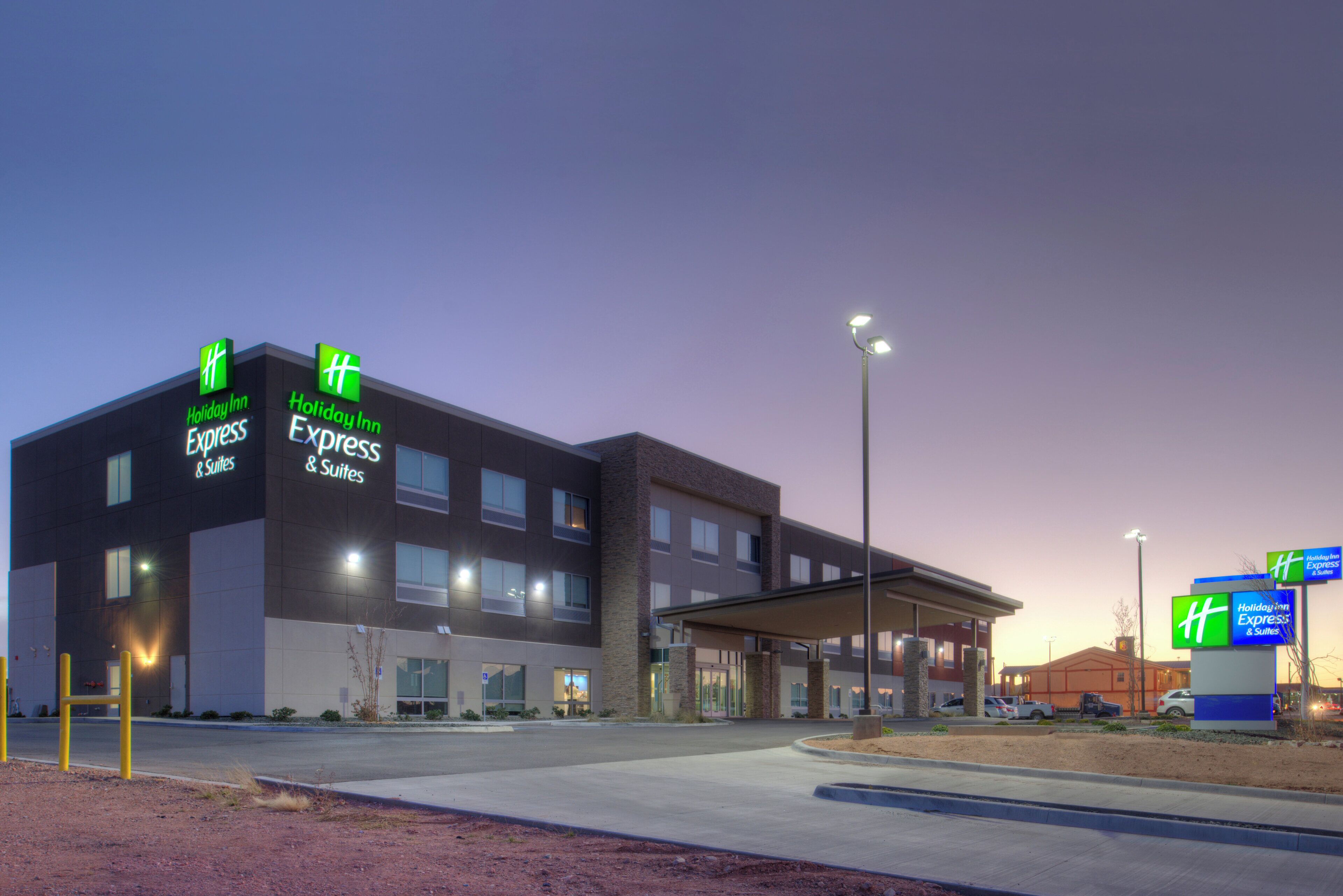 Edifício do Holiday Inn Express & Suites com design moderno, apresentando um telhado plano e grandes janelas.