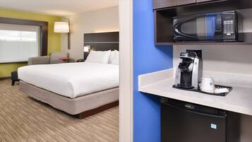 Ein Hotelzimmer mit einem Bett, einem Schreibtisch mit Kaffeemaschine, einer Mikrowelle und einem kleinen Kühlschrank.