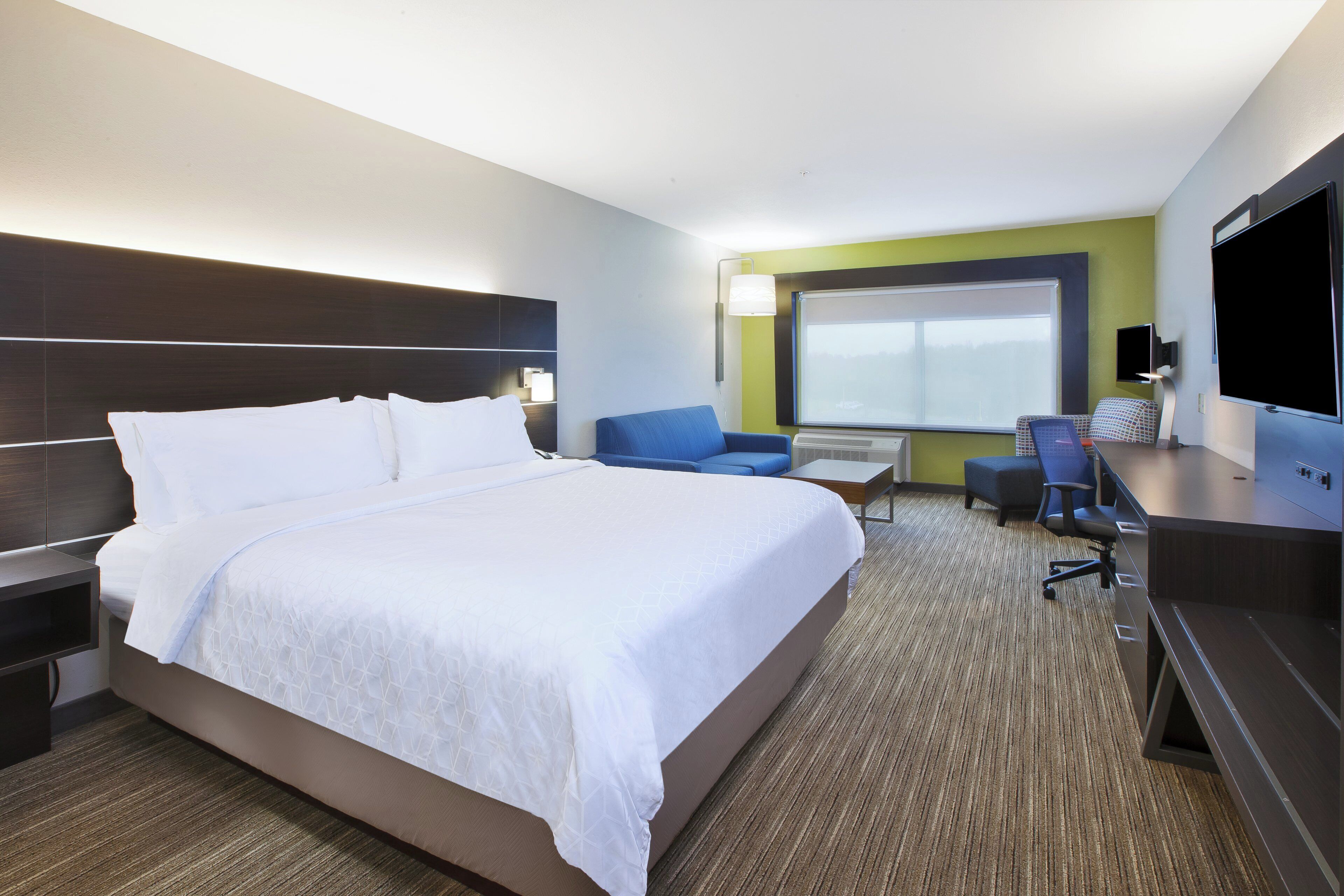 Una habitación de hotel con una cama grande, un escritorio, una silla, un televisor y una ventana.