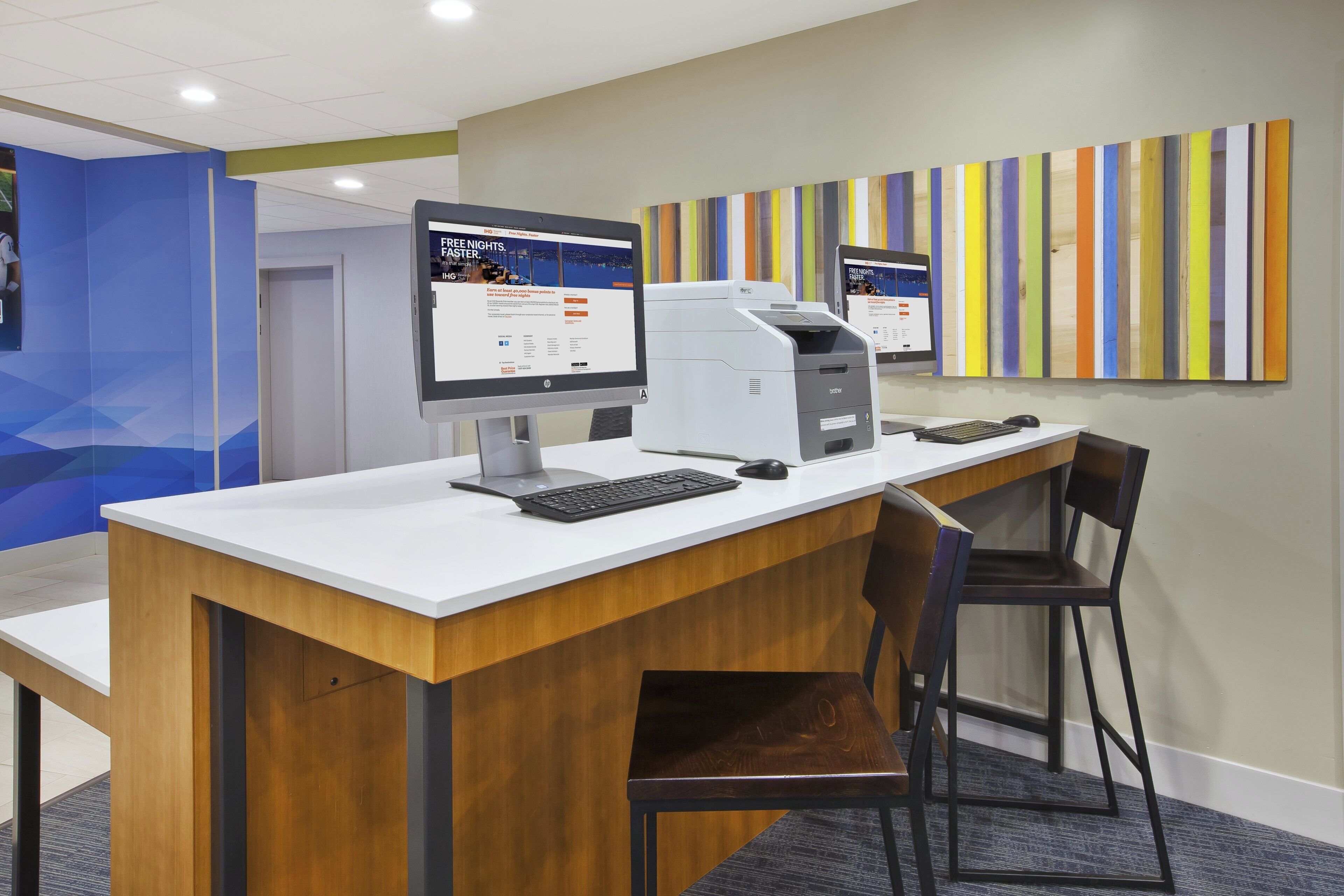 Een receptiebalie met een computer, printer en toetsenbord. Er staat een stoel en er is een muur met verticale strepen.