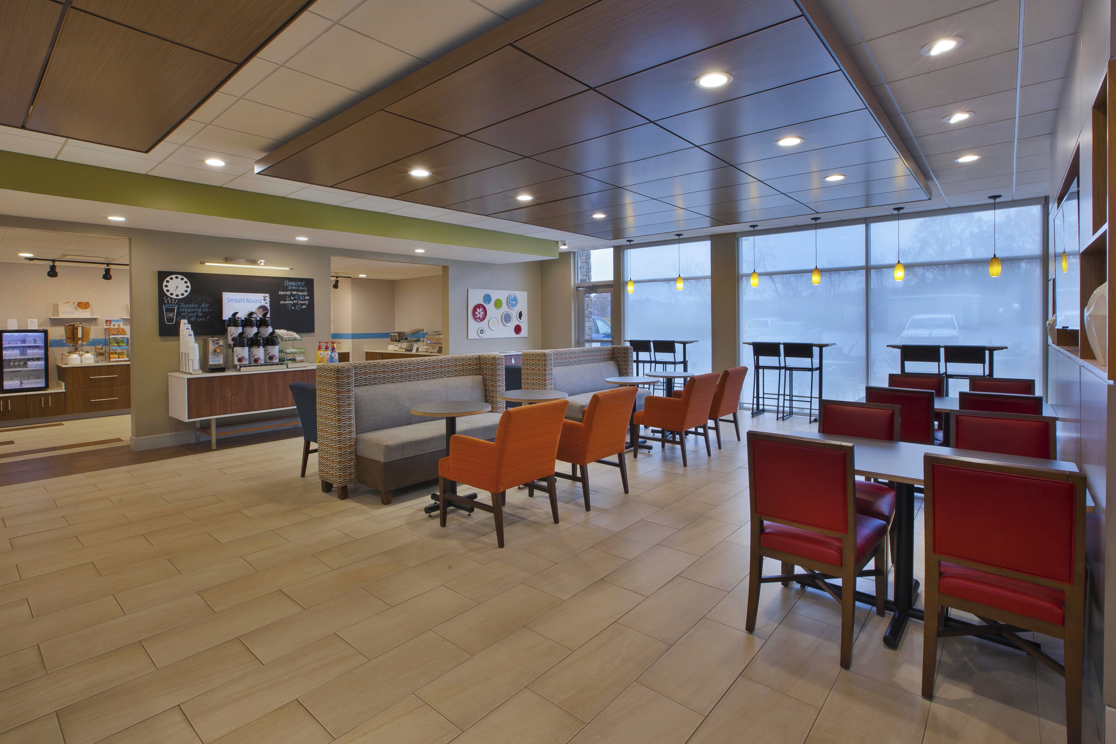 A modern cafe with seating areas, a counter with coffee machines, and a menu board.