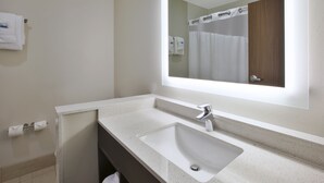 A modern bathroom with a large mirror, a sink, and a shower area.